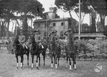 Quattro ufficiali a cavallo sull'attenti davanti alla Casina dell'Orologio, a Piazza di Siena