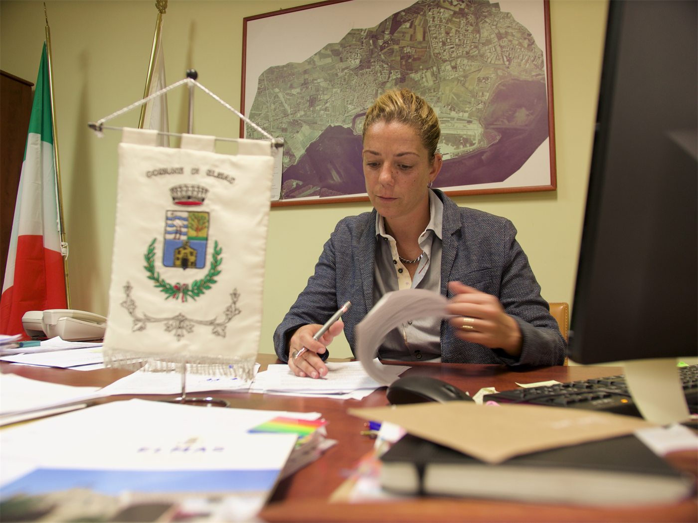 Alla scrivania del Comune di Elmas, con il gonfalone comunale