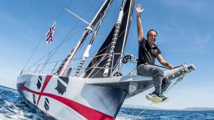 Andrea Mura seduto sul bompresso di Vento di Sardegna saluta con il braccio alzato